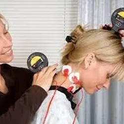 A person undergoing surface electromyography with sensors and measuring devices attached to the neck and head.