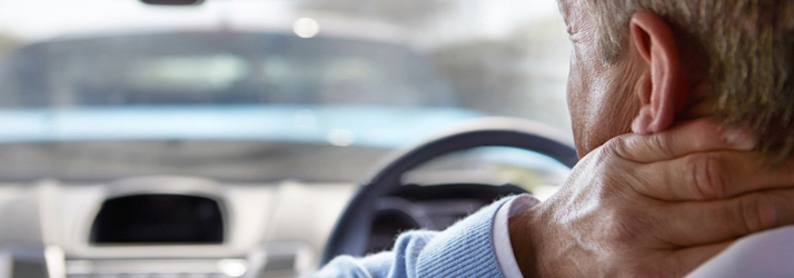 Person in a car holding the neck, suggesting discomfort.