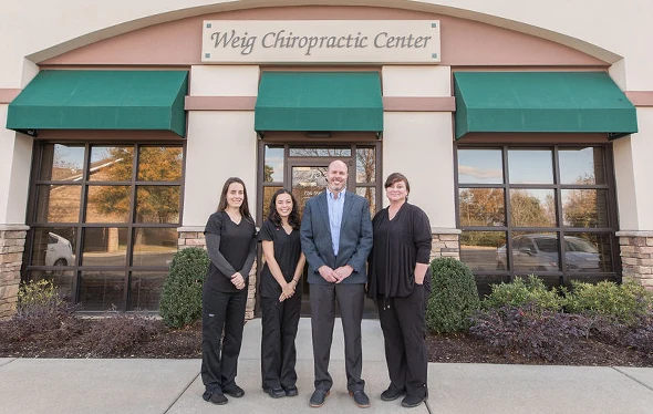 Dr. Toby Weig with staff members in front of a building with a sign that reads “Weig Chiropractic Center.”